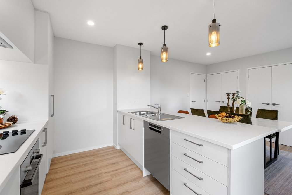 Completed Ashcroft kitchen, white cabinetry with pendant lighting and stone benchtop.