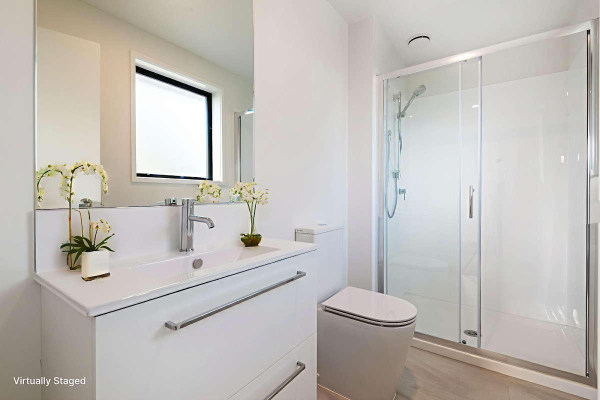 Interior of a completed Ashcroft home — a bathroom with porcelain tile and warm oak cabinetry.